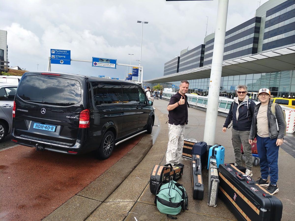 Taxibus van Taxi Centrale Nijmegen bij de vertrekhal van Schiphol, met passagiers en hun bagage