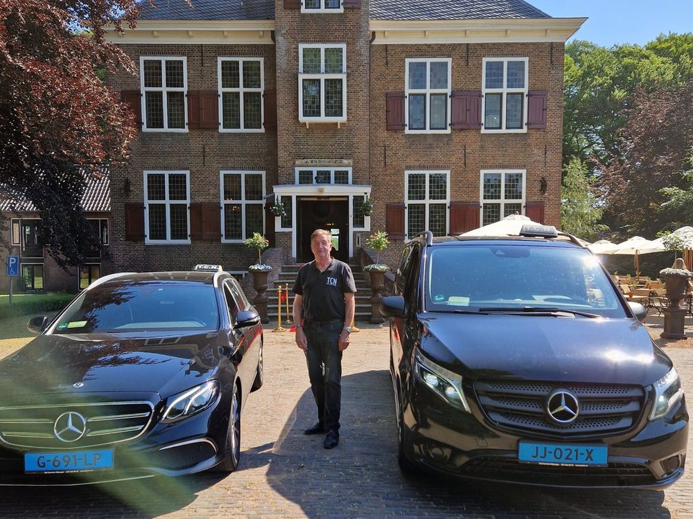 Chauffeur van Taxi Centrale Nijmegen bij de Mercedes E-klasse en de 8-persoons taxibus